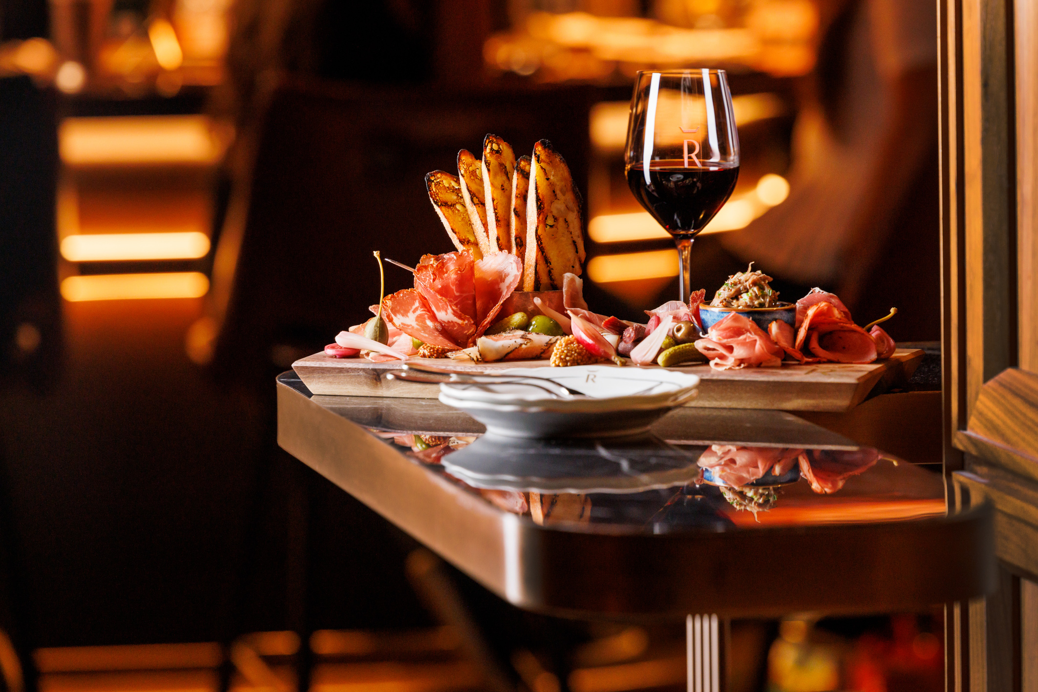 A charcuterie meat board and glass of red wine.