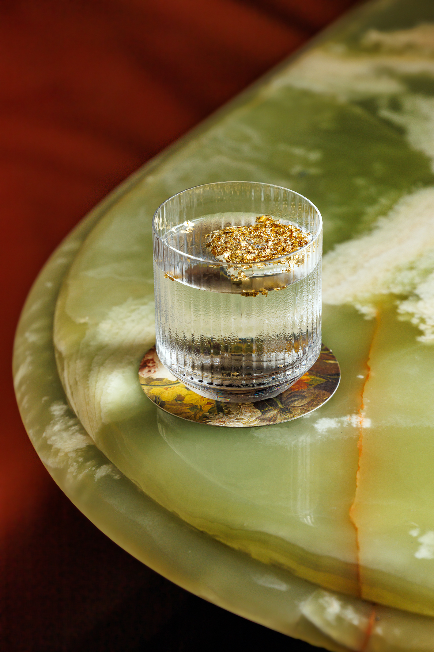 A clear cocktail with confection garnish on a marble tabletop.