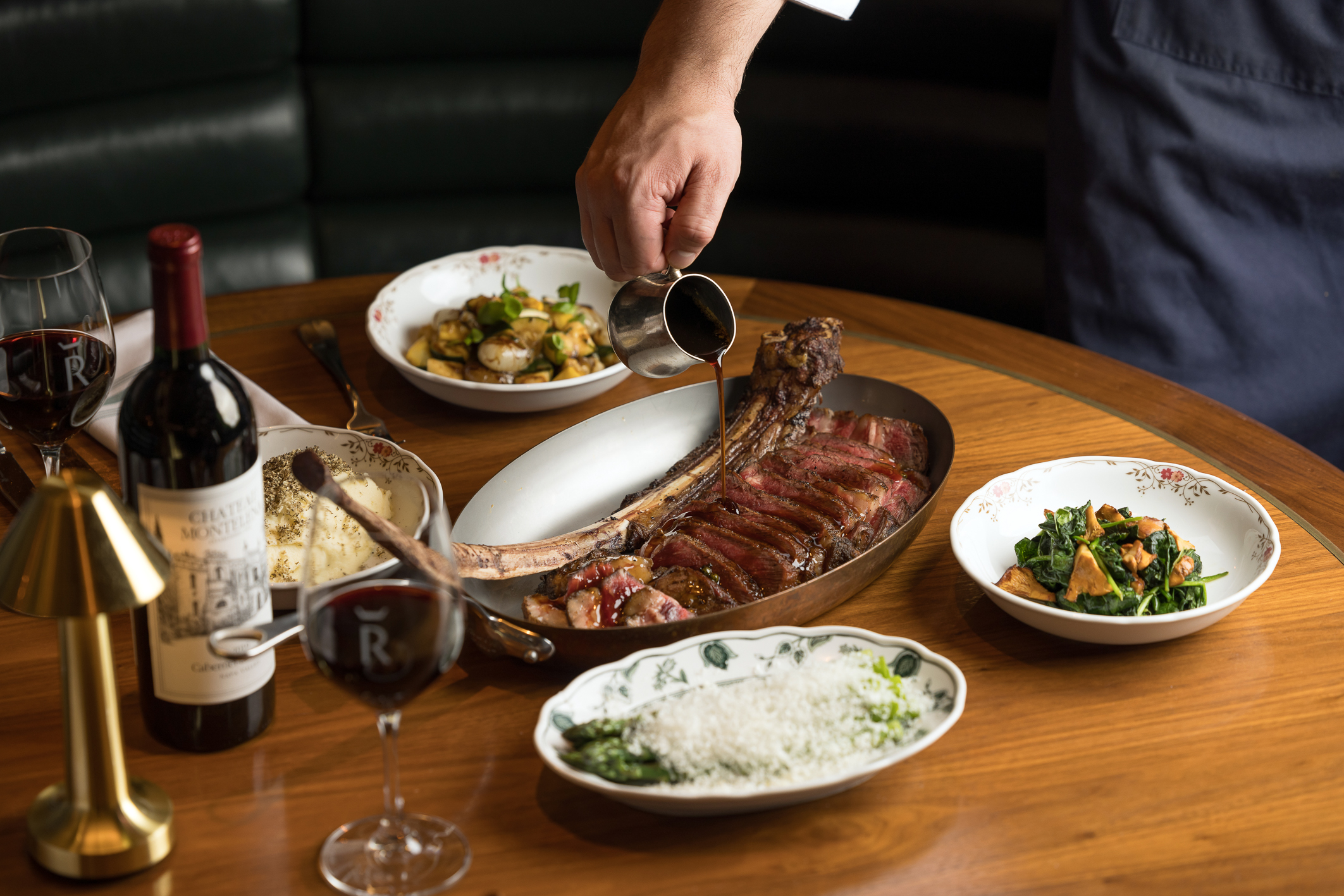 A chef pouring sauce over steak
