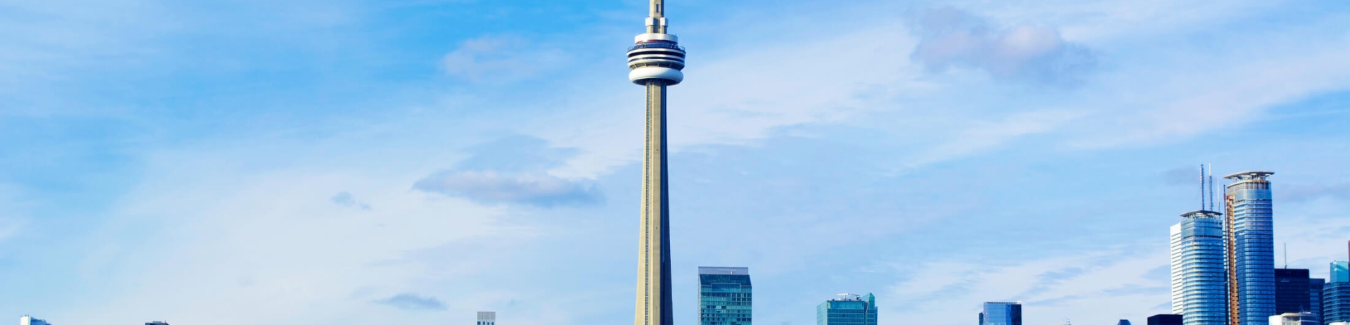 The CN Tower and Rogers stadium in the Toronto skyline on a clear blue-skied day.
