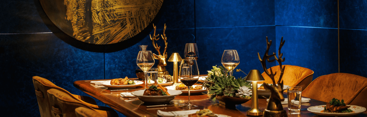 A long wooden table with wine and plates of food.