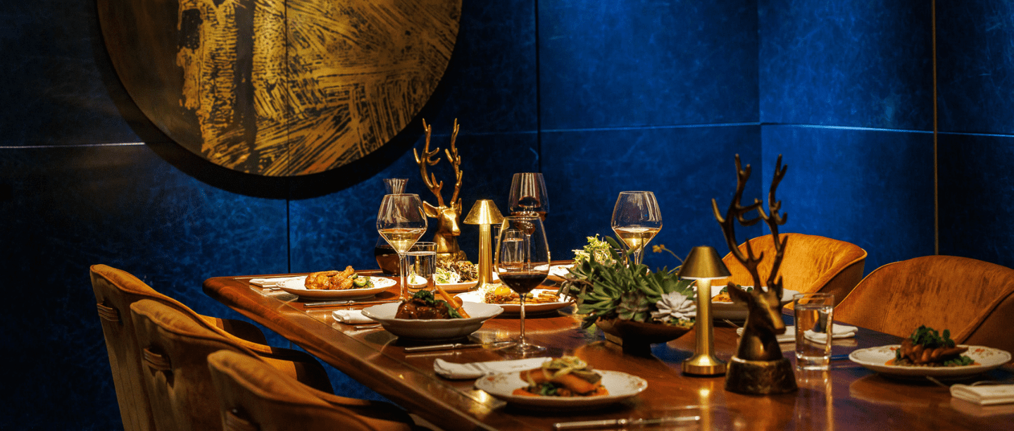 A long wooden table with wine and plates of food.