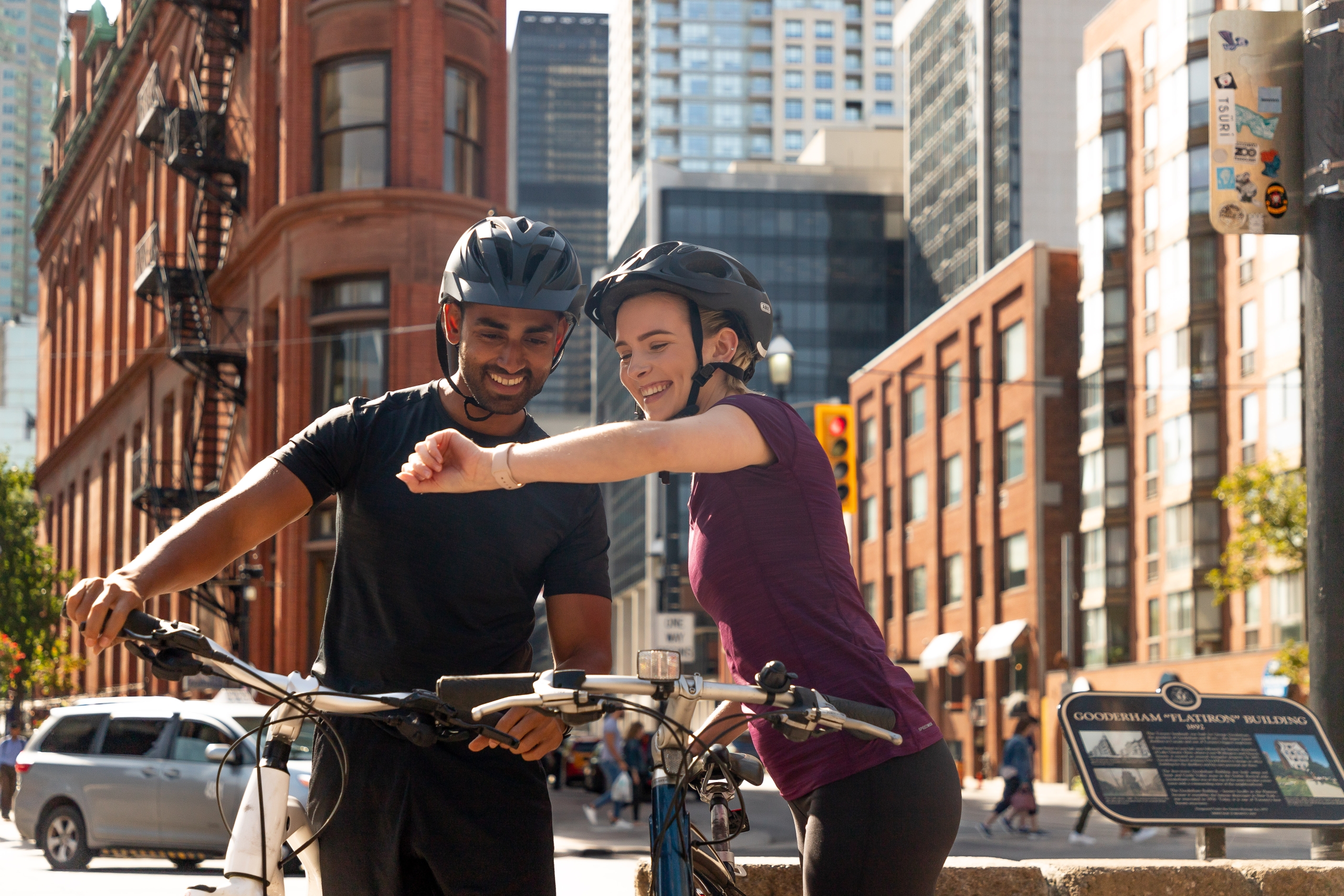 A couple walking bikes by the Flatiron building in Toronto